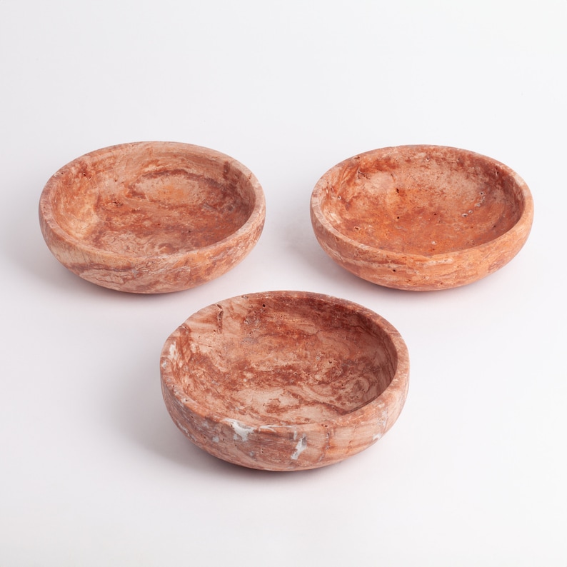 May include: Three small, round, brown and white marble bowls. The bowls are made of a natural stone with a swirling pattern.