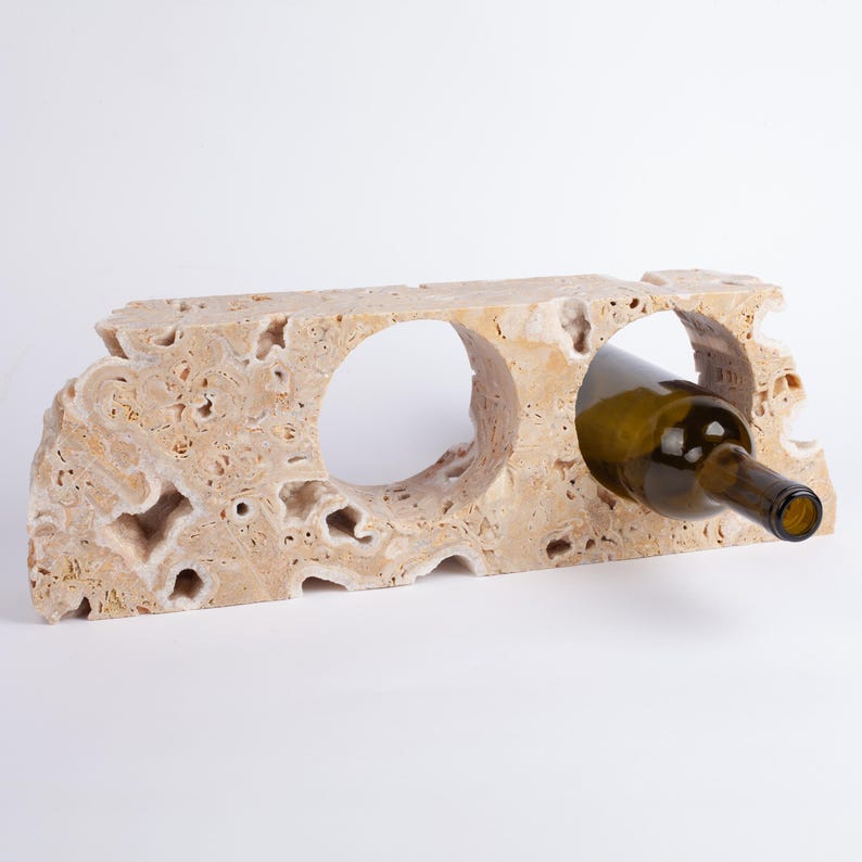 May include: A beige travertine wine bottle holder with two openings. One opening has a wine bottle in it.