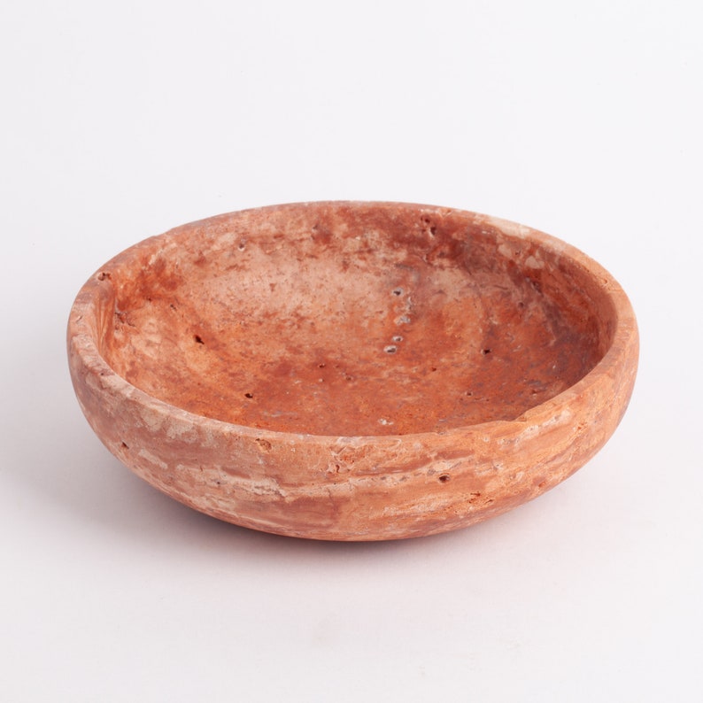 May include: A terracotta bowl with a rough, textured surface. The bowl has a wide, shallow shape and a slightly uneven rim.