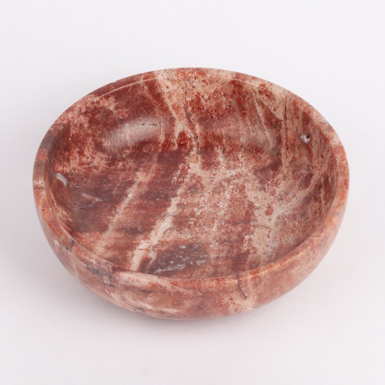 May include: A round, red and white marble bowl with a smooth, polished finish.