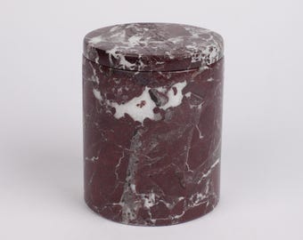 May include: A round, red and white marble container with a lid. The container has a swirling pattern of red and white marble.