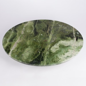 May include: Oval-shaped green marble tabletop with a natural, veined pattern. The stone features shades of green and white, creating a unique and organic design. The tabletop is smooth and polished, ideal for a coffee table or decorative surface.