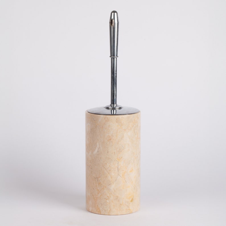 May include: A beige marble toilet brush holder with a chrome handle.
