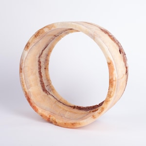 May include: A large, round, white and brown ring made of alabaster. The ring is smooth and has a natural, organic look.