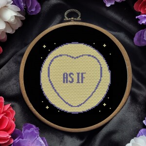 May include: A yellow heart-shaped candy with the text "AS IF" in purple letters on a black background with white stars.