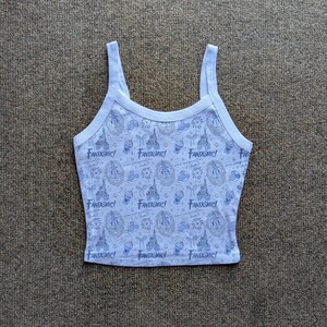 May include: A light blue tank top with a white trim and straps. The tank top features a repeating pattern of castles, Mickey Mouse, fireworks, and the word "Fantasmic!".
