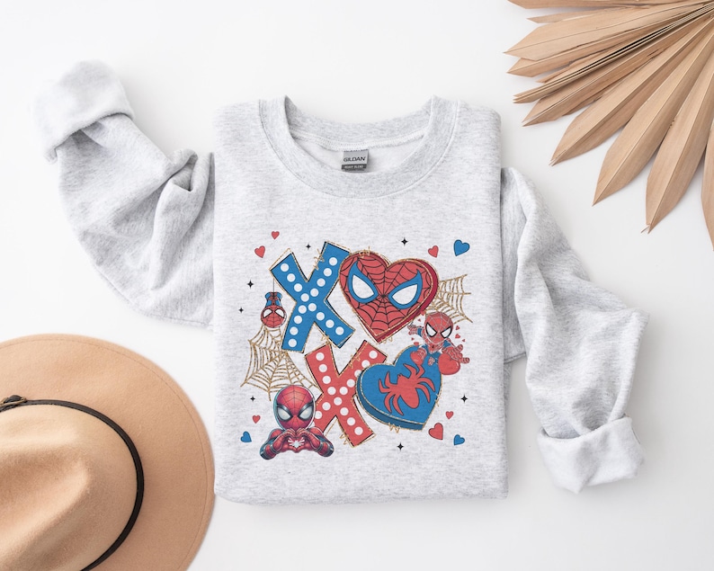 Puede incluir: Sudadera gris con un gr&aacute;fico de Spiderman rojo y azul. El gr&aacute;fico presenta la cara de Spiderman, un coraz&oacute;n y las letras XOXO.