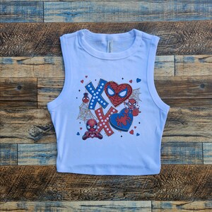 Puede incluir: Top corto blanco sin mangas con un estampado gr&aacute;fico de Spiderman en un coraz&oacute;n con XOXO y otros dise&ntilde;os con tem&aacute;tica de Spiderman.