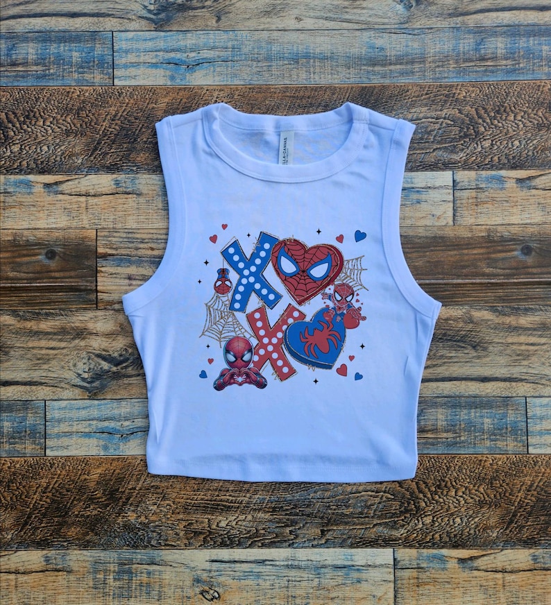 Puede incluir: Top corto blanco sin mangas con un estampado gr&aacute;fico de Spiderman en un coraz&oacute;n con XOXO y otros dise&ntilde;os con tem&aacute;tica de Spiderman.