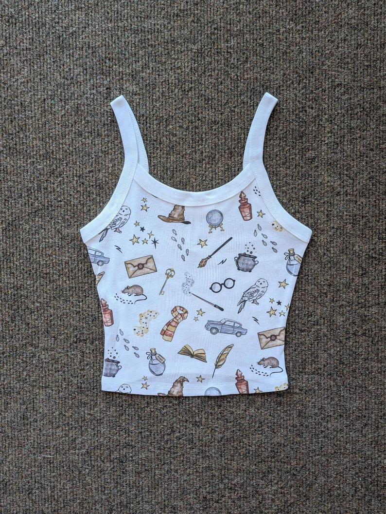 May include: White tank top with a pattern of various Harry Potter themed illustrations, including a wizard's hat, glasses, a wand, a book, a potion bottle, a owl, a car, and a letter.