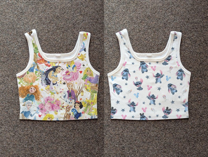 Puede incluir: Dos tops cortos blancos con cuello cuadrado. Uno presenta un collage colorido de princesas y personajes de Disney. El otro tiene un patr&oacute;n del personaje Stitch, cabezas de Mickey Mouse rosas y estrellas.