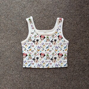 Puede incluir: Top corto blanco con un estampado colorido con Mickey Mouse, Minnie Mouse, Donald Duck y Daisy Duck. El top sin mangas tiene cuello redondo y tirantes anchos. La tela es un material suave y ligero.