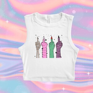 May include: White sleeveless crop top featuring a graphic of four hands giving the middle finger. The hands are depicted in various styles: a skeleton hand, a pink furry hand, a green hand, and a wrapped hand.