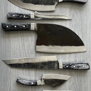 May include: A set of six black-handled kitchen knives with different blade shapes and sizes. The knives are arranged in a row on a gray surface.