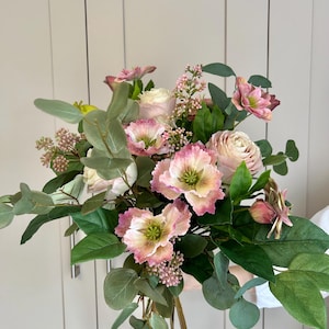 May include: A vibrant bouquet of mixed flowers, including pink and white roses, anemones, and eucalyptus leaves. The arrangement has green foliage and a variety of textures, creating a natural and colourful display.