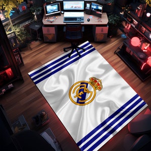 Puede incluir: Alfombra blanca y azul con un logotipo de equipo de f&uacute;tbol en el centro. El logotipo es un c&iacute;rculo blanco con una estrella azul y una corona dorada en la parte superior. La alfombra tiene un fondo blanco con rayas azules.