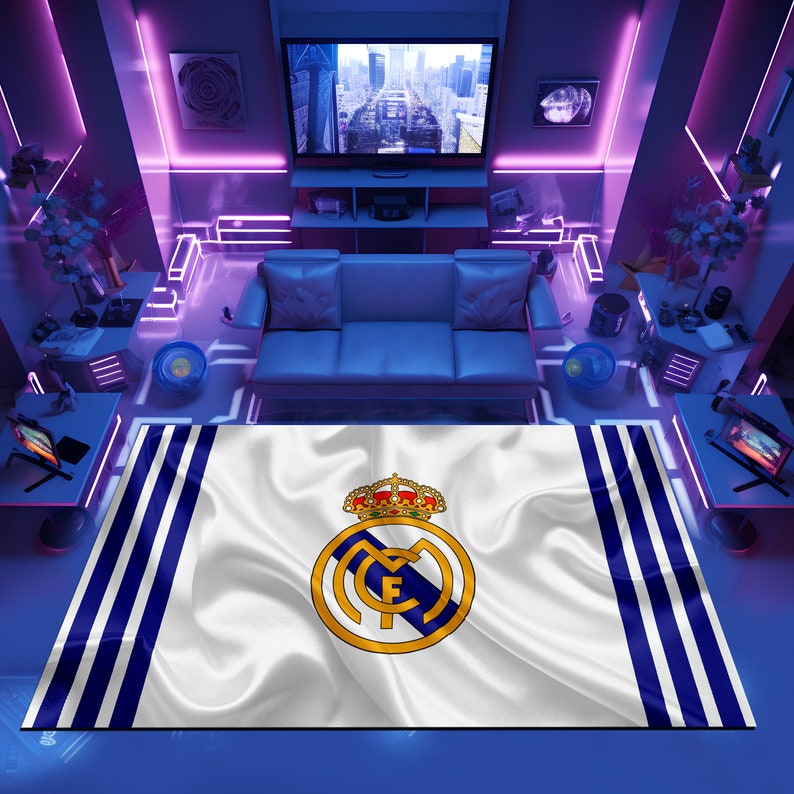 Puede incluir: Una alfombra blanca y azul con el escudo del Real Madrid en el centro. El escudo presenta una corona dorada, una letra "M" blanca y una letra "F" blanca dentro de un c&iacute;rculo azul.