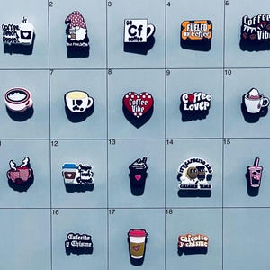 May include: A collection of eighteen colorful shoe charms featuring various coffee-themed designs, including cups, mugs, hearts, and text such as Coffee Teach Repeat, Fueled by Coffee, Coffee Vibe, Coffee Lover, Cafecito y Chisme, and It's Cafecito and Chisme Time.