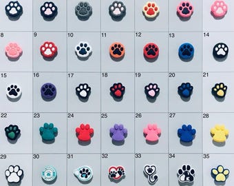 May include: Thirty-five different colored paw print designs. The paw prints are made of silicone and are designed to be used as phone grips or pop sockets.