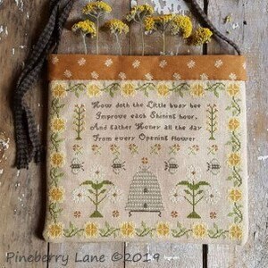May include: A beige and brown cross-stitch sampler with a beehive and flowers. The sampler has a quote that reads: "How doth the little busy bee Improve each shining hour. And gather honey all the day From every opening flower."