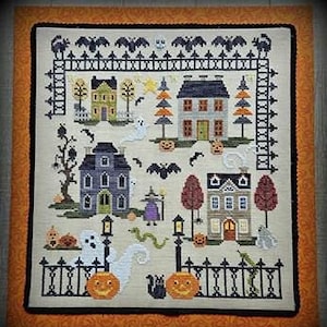 May include: Cross-stitch pattern featuring a spooky Halloween village with houses, trees, pumpkins, ghosts, bats, and a witch. The pattern is framed with a black fence and a black border.