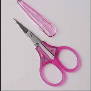 May include: Pink nail scissors with a silver blade and a pink plastic case.