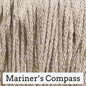 May include: Close-up of a beige embroidery floss skein with the text "Mariner's Compass" printed on the label.