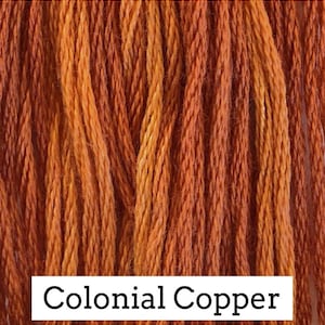 May include: Close-up of a bundle of embroidery floss in a warm orange and yellow color. The floss is labeled "Colonial Copper".