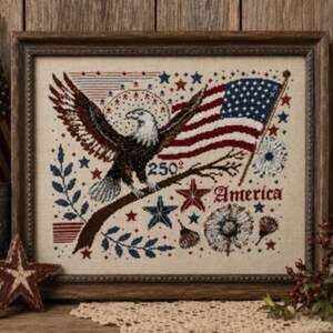 May include: A framed cross-stitch embroidery featuring a bald eagle perched on a branch with an American flag, stars, and floral motifs. The design includes the text 250 and America in red and blue thread on a light beige fabric background.