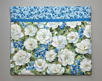 May include: A green zippered pouch with a white floral pattern and blue forget-me-not flowers. The pouch is lined with a blue fabric with a small white floral pattern.