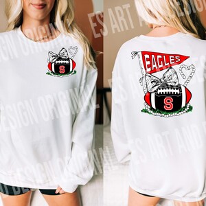 May include: White sweatshirt with a red and black football design. The football has a red bow and a pearl necklace. The text "EAGLES" is on a red pennant.