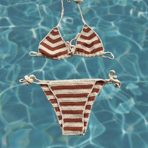 Puede incluir: Un top y una parte inferior de bikini de crochet a rayas marrones y blancas. El bikini está colocado sobre una superficie de azulejos azules.