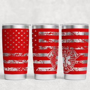 Puede incluir: Tres vasos de acero inoxidable con un diseño de bandera estadounidense desgastado. El vaso del centro tiene un logotipo de bombero y EMS plateado.