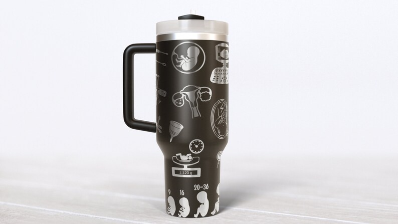 May include: Black travel mug with a white design of medical symbols and illustrations related to pregnancy and childbirth. The mug has a black handle and a silver lid.