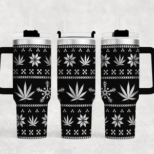 May include: A black and silver stainless steel tumbler with a handle and a lid. The tumbler has a Christmas-themed design with snowflakes and marijuana leaves.