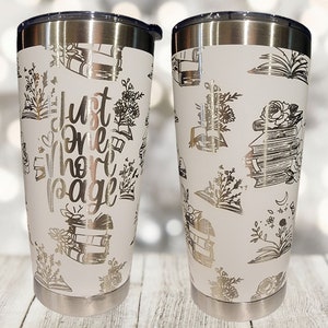 May include: Two white stainless steel tumblers with a silver lid. The tumblers are decorated with a pattern of books, flowers, and the text "Just One More Page".