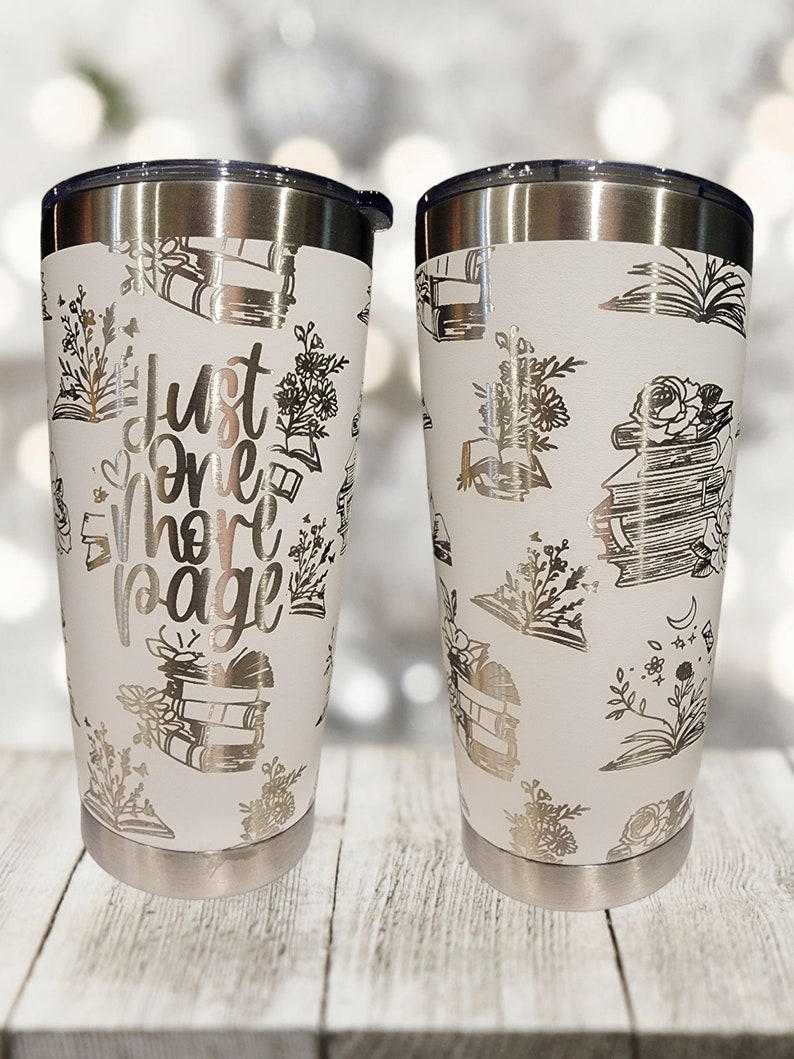 May include: Two white stainless steel tumblers with a silver lid. The tumblers are decorated with a pattern of books, flowers, and the text "Just One More Page".