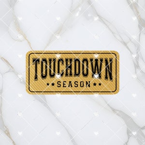 May include: A gold-colored rectangular sign with the text "TOUCHDOWN SEASON" in black lettering. The sign has a textured background.