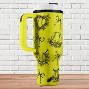 Könnte beinhalten: Gelbe Reisebecher mit schwarzem Griff und einem Design aus Softball, Schleifen und Blumen.