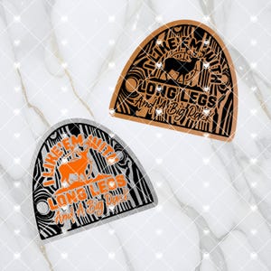 May include: Two wood-grain patterned, half-circle shaped decals with a black silhouette of a deer and the text "Like 'em with long legs and a big rack". One decal is brown and the other is silver.