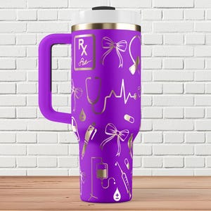 May include: Purple stainless steel travel mug with a white lid and a handle. The mug has a gold design of medical symbols, including a stethoscope, a heart rate, a pill, a syringe, a bow, and the text "Rx".