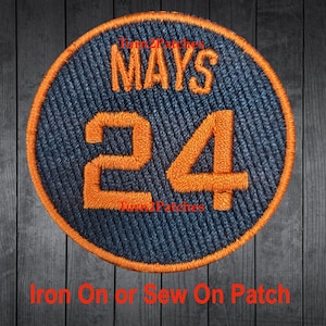 May include: A round, navy blue iron-on or sew-on patch with orange stitching. The patch features the name "MAYS" in orange lettering and the number "24" in large orange numerals.