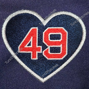 May include: Embroidered heart-shaped patch with the number 49 in red, outlined in white, on a navy blue background. The patch is likely for clothing or accessories.