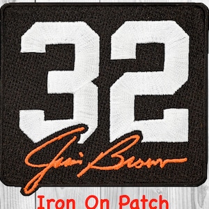 May include: Black square patch with the number 32 in white, and an orange signature below. The patch has an embroidered texture. The words "Iron On Patch" are at the bottom in orange.