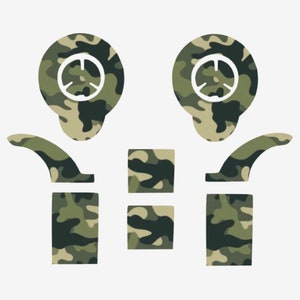 May include: A collection of camouflage-patterned decals in shades of green, brown, and tan. The set includes two circular shapes with a white design, two curved shapes, two rectangular shapes, and two square shapes.