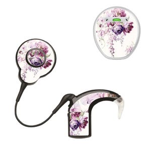 Puede incluir: Un conjunto de tres audífonos. Los dispositivos están decorados con un estampado floral de flores moradas y blancas. Los dispositivos son negros y blancos.