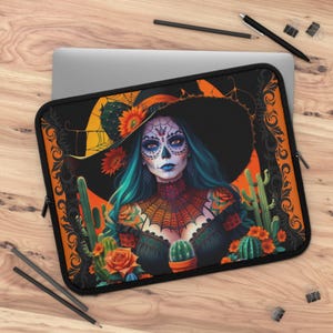 Può includere: Custodia per laptop nera con un'illustrazione colorata di una donna con trucco da teschio di zucchero, capelli turchesi e un grande cappello nero. Il design include cactus, fiori e una ragnatela, su sfondo arancione.