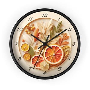 May include: Round wall clock with a black frame and a cream-colored face. The clock face features a decorative design of orange slices, leaves, and floral elements. The clock hands are black.