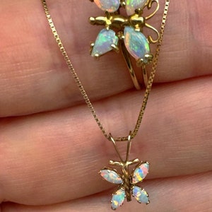 May include: A gold chain necklace with a butterfly pendant. The butterfly is made of opal stones and has a delicate design. The chain is a box chain style.