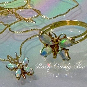 May include: Two gold necklaces with iridescent butterfly pendants. The necklaces are layered and the butterflies are different sizes. The text "Rock Candy Bar" is visible in the image.